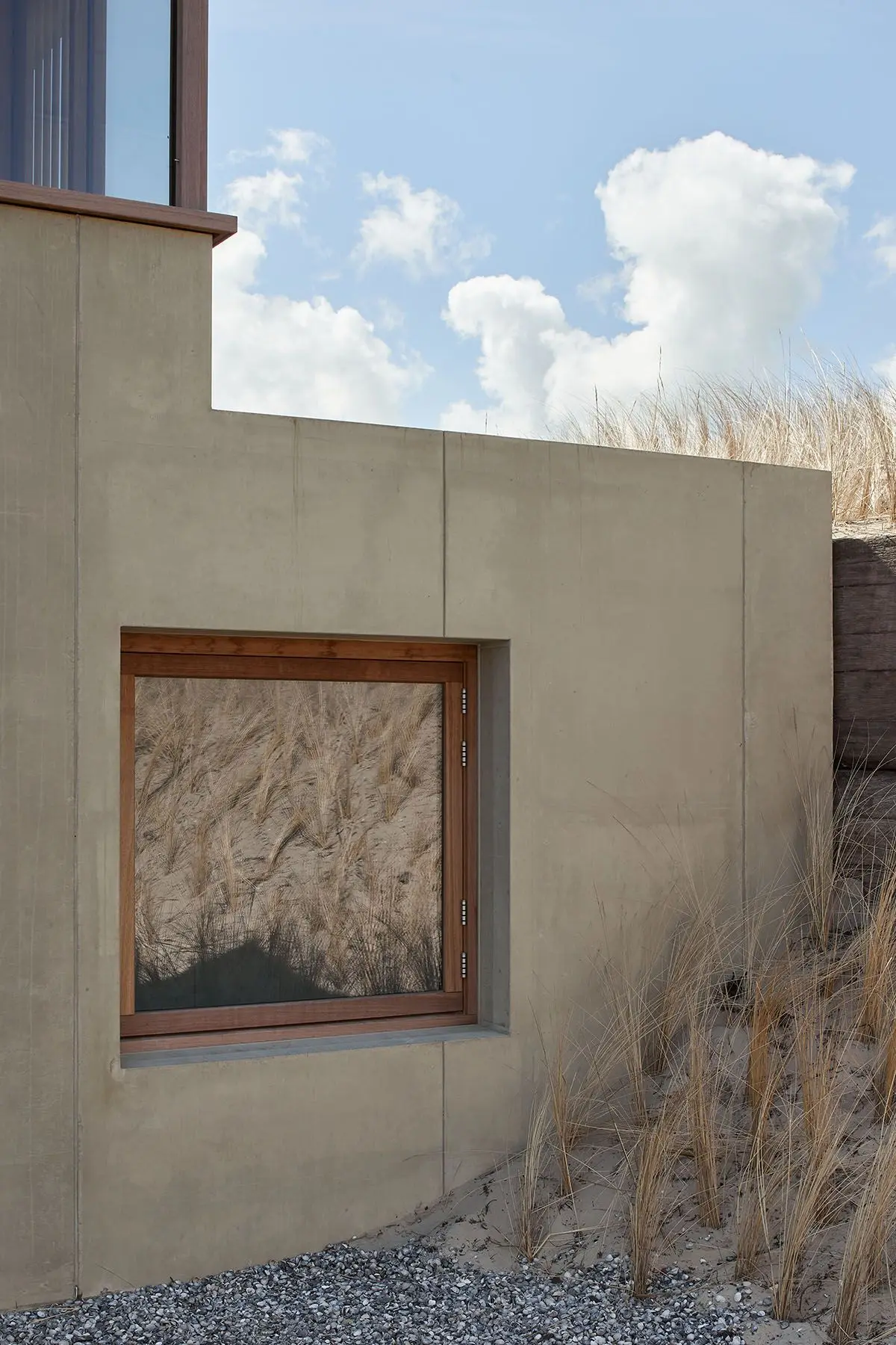 Huis in de duinen: betonnen plint met houten kozijn tussen het helmgras. Foto: MWA Hart Nibbrig