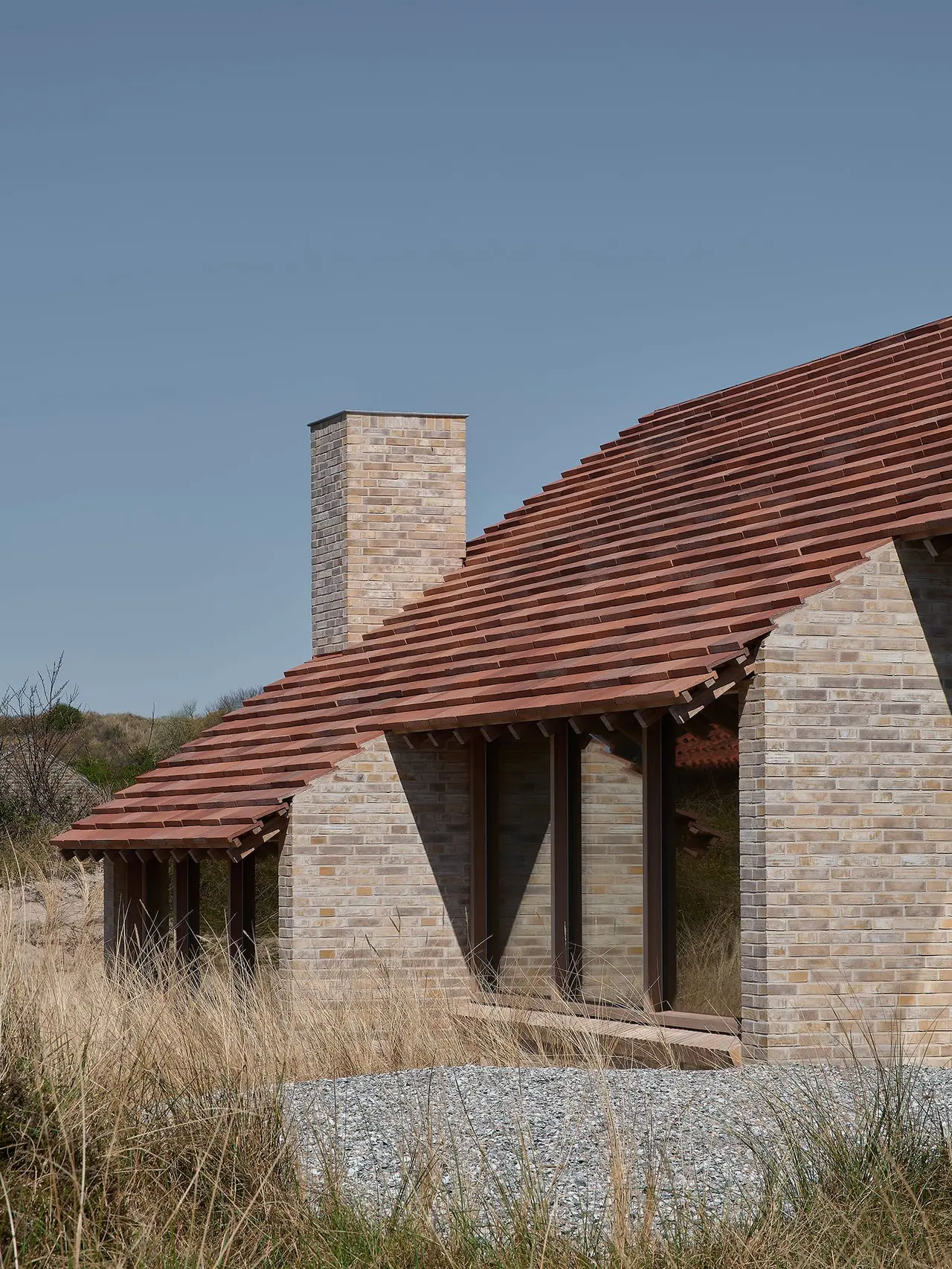 House on a Dune: de zandkleurige bakstenen kopgevel en het rode pannendak boven het helmgras.